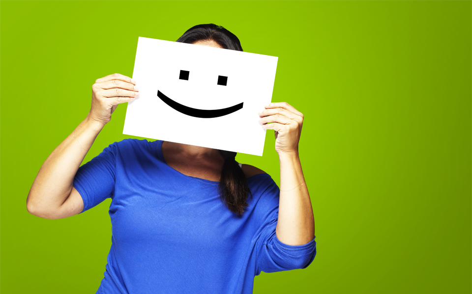 Fata cu o bluză albastră cu un smiley pus pe față.